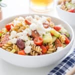 Greek pasta salad in a white serving bowl on a white countertop