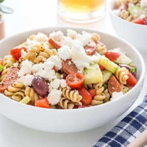 Greek pasta salad in a white serving bowl on a white countertop