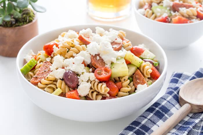 Greek pasta salad in a white serving bowl on a white countertop