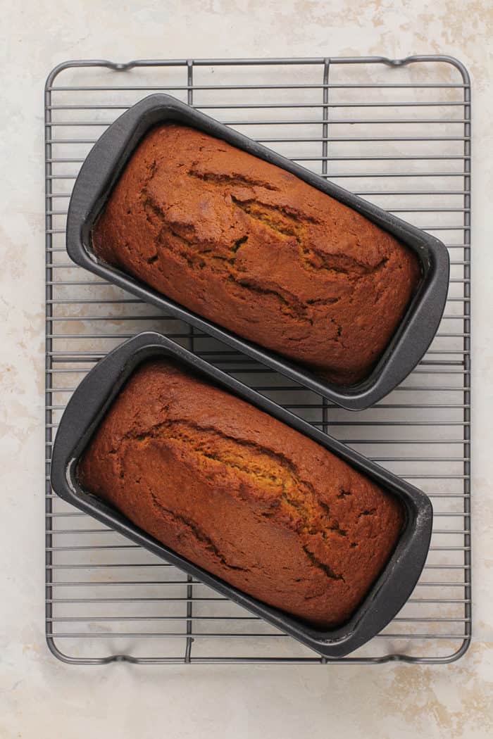 Two baked loaves of pumpkin bread cooling on a wire rack