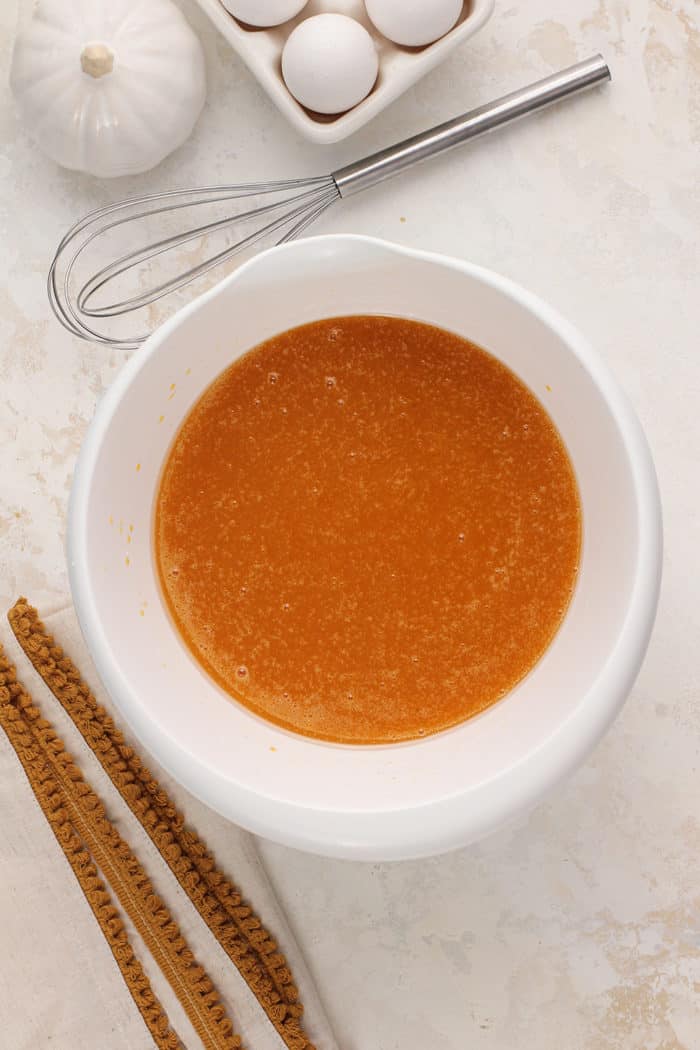 Wet ingredients for pumpkin bread in a white mixing b owl