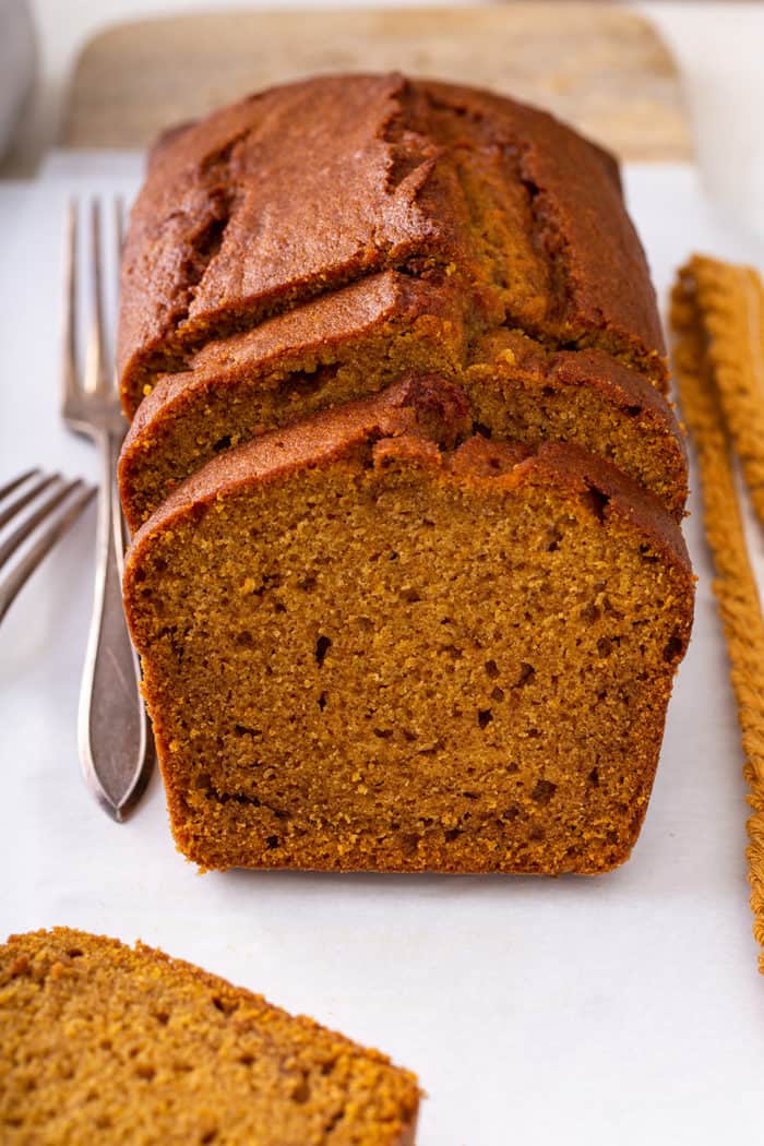 Sliced loaf of pumpkin bread on a white cutting board