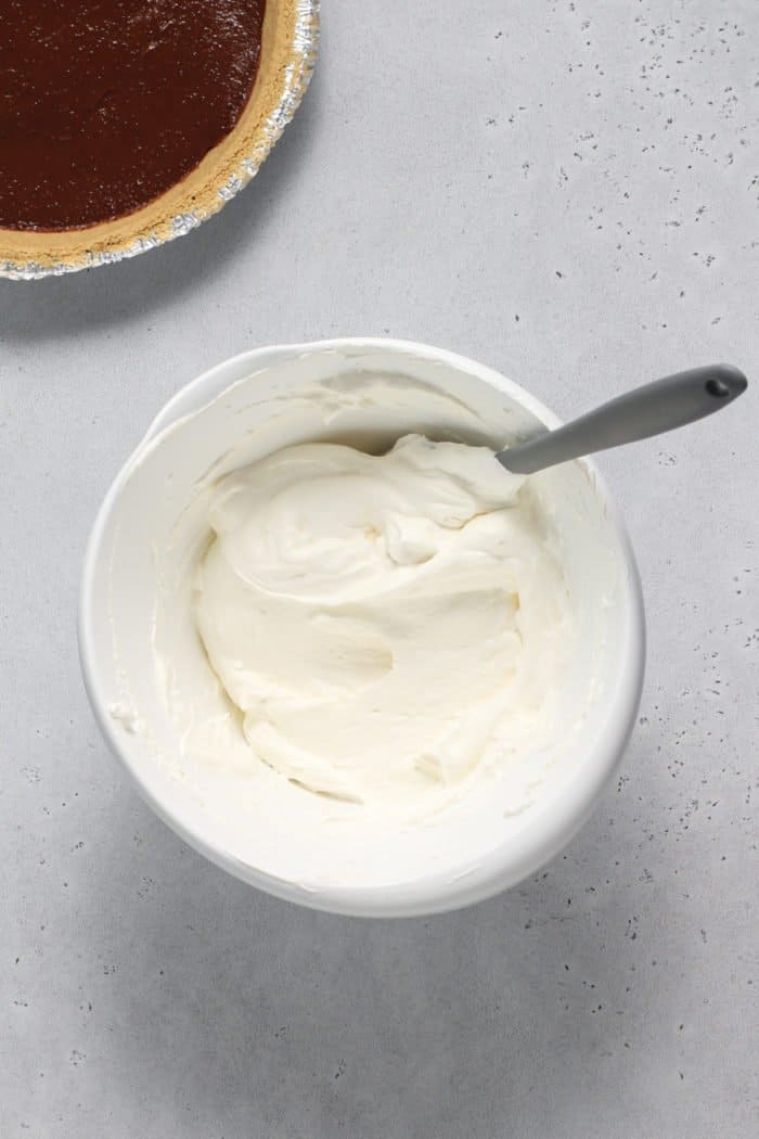 Topping for s'mores pie being folded together in a white mixing bowl.