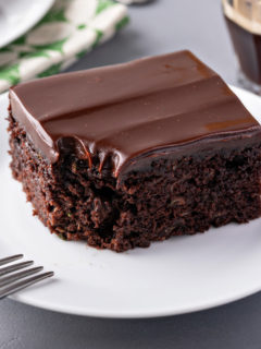 Slice of chocolate zucchini cake with a bite taken out of the corner.