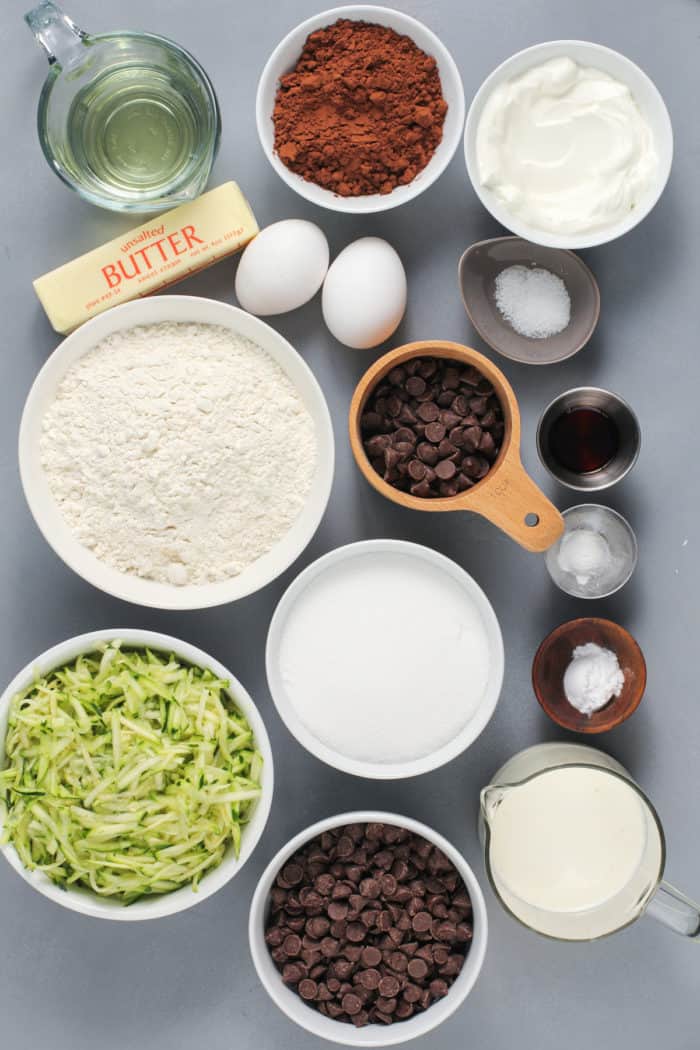 Ingredients for chocolate zucchini cake arranged on a gray countertop.