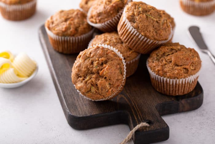 Close up of morning glory muffins piled on a wooden board.