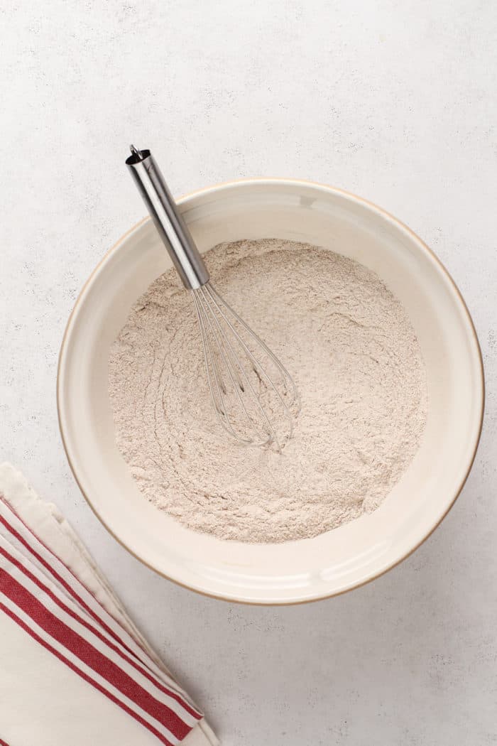 Dry ingredients for morning glory muffins being whisked together in a ceramic mixing bowl.