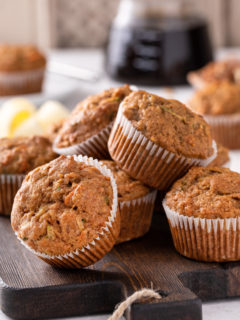 Morning glory muffins piled on a wooden board.