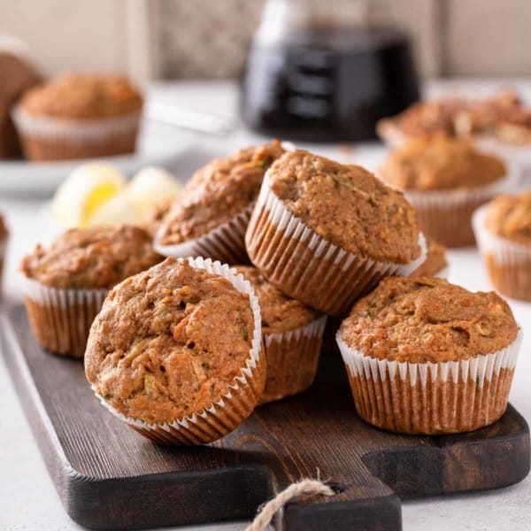 Morning glory muffins piled on a wooden board.