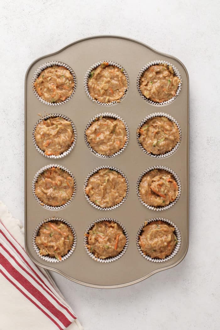 Morning glory muffin batter in a muffin tin, ready to go in the oven.