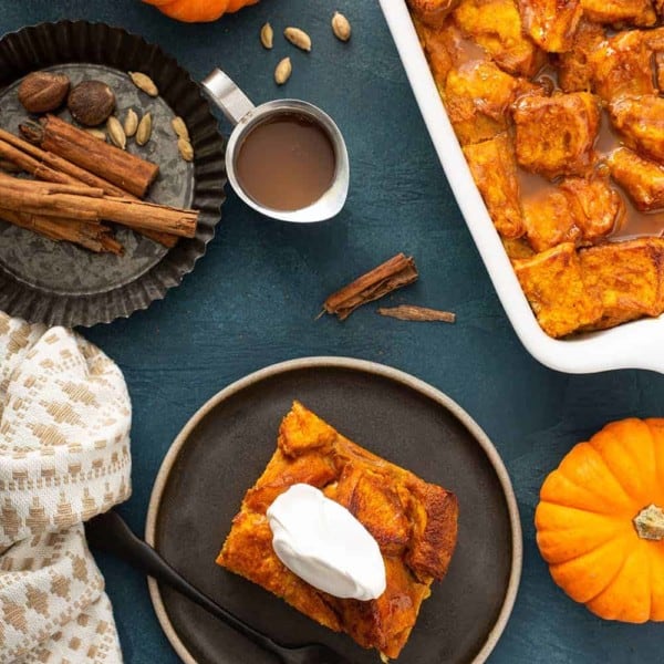 Overhead view of a plated slice of bread pudding next to a baking dish of pumpkin bread pudding