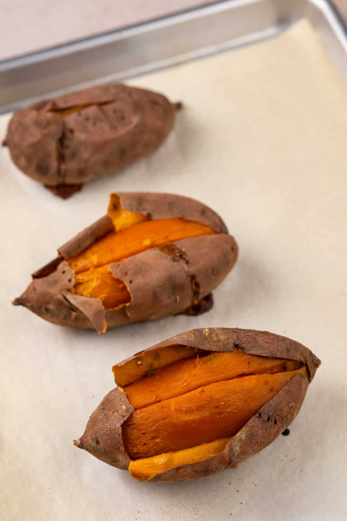 Baked sweet potatoes with their skins open to show their cooked centers.