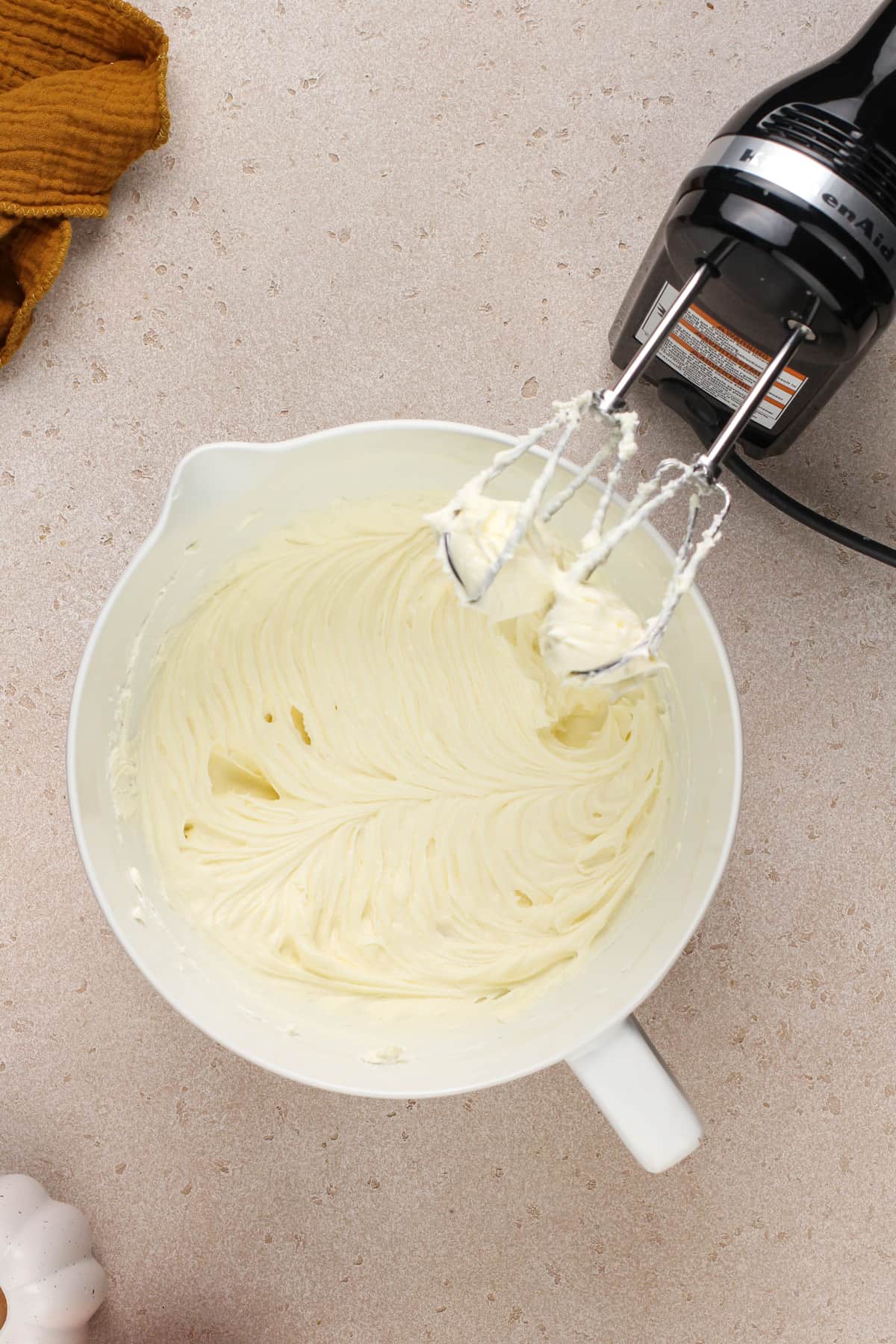 Cream cheese and sugar beaten together in a white mixing bowl.