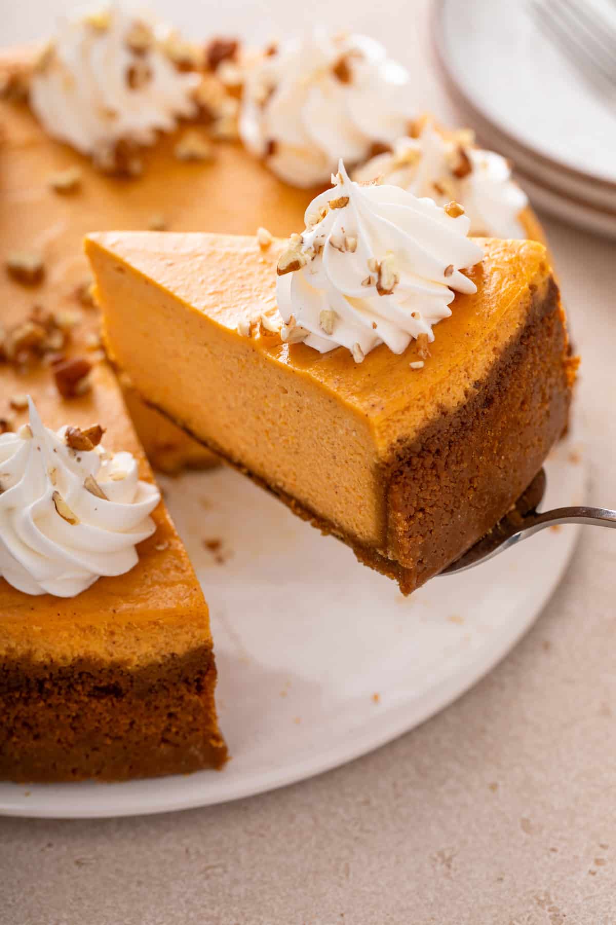 Cake server lifting a slice of sweet potato cheesecake from a cake plate.
