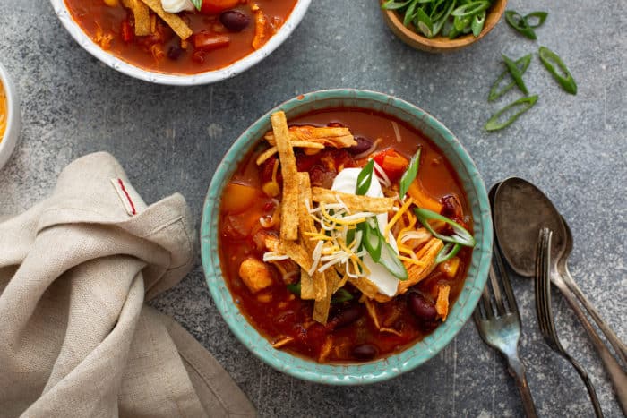 Easy chicken chili topped with sour cream and cheese in a blue bowl