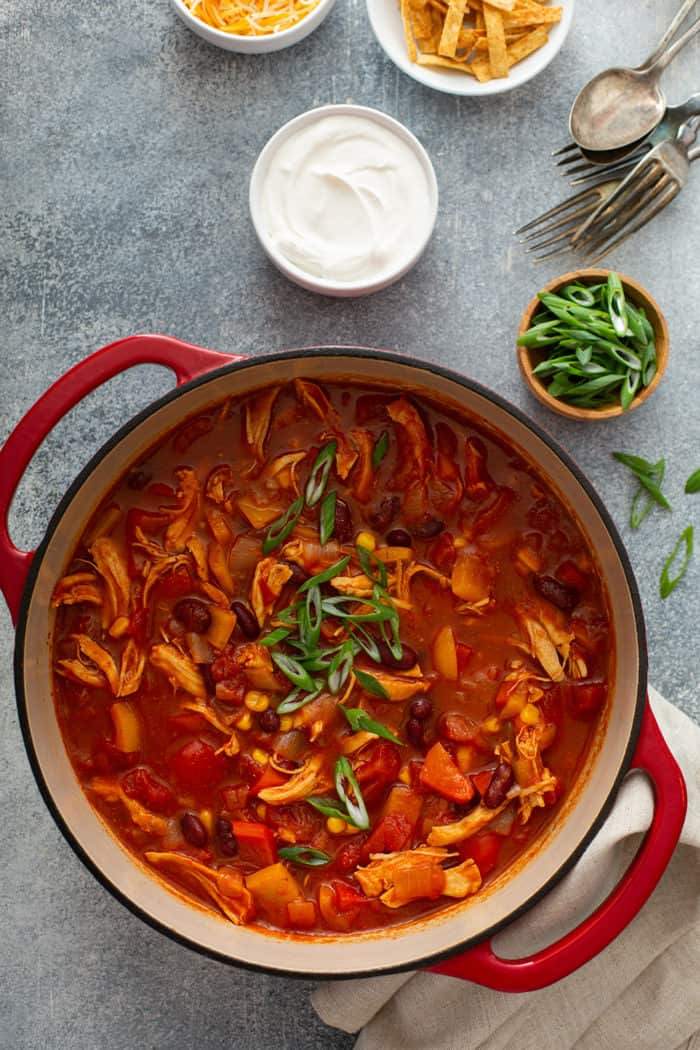 Chicken chili topped with green onions in a red dutch oven