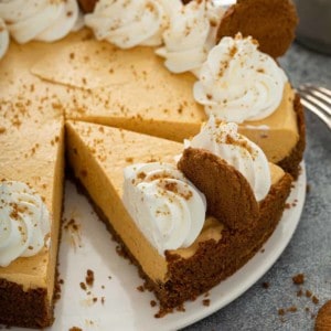 Sliced marshmallow pumpkin pie garnished with whipped cream and gingersnap cookies