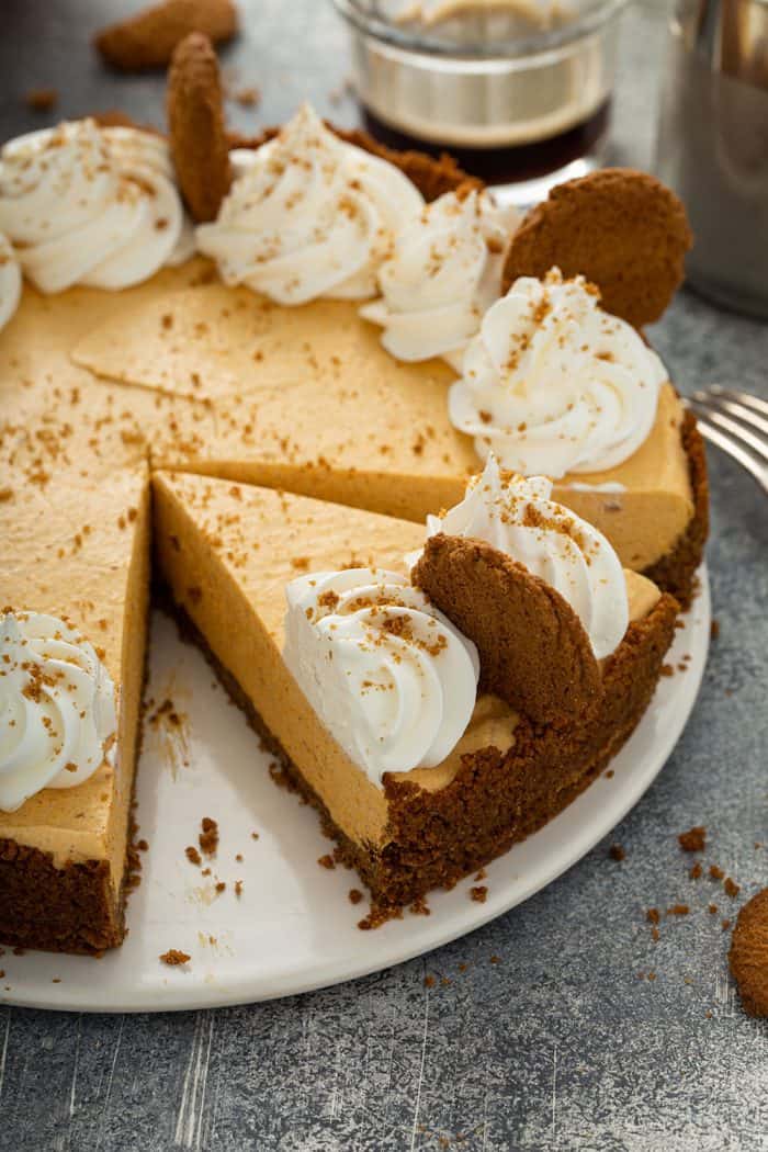 Sliced marshmallow pumpkin pie garnished with whipped cream and gingersnap cookies