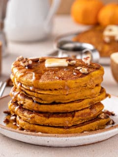 Stack of pumpkin pancakes topped with butter and syrup.