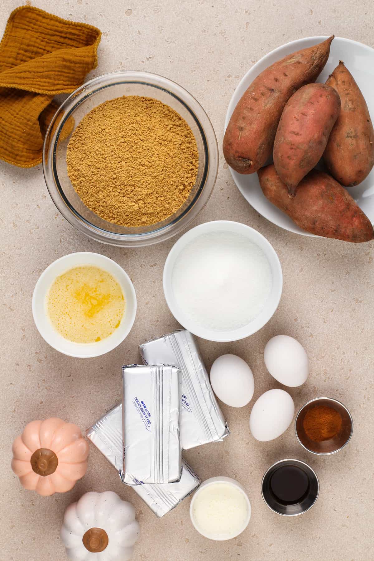 Ingredients for sweet potato cheesecake arranged on a beige countertop.