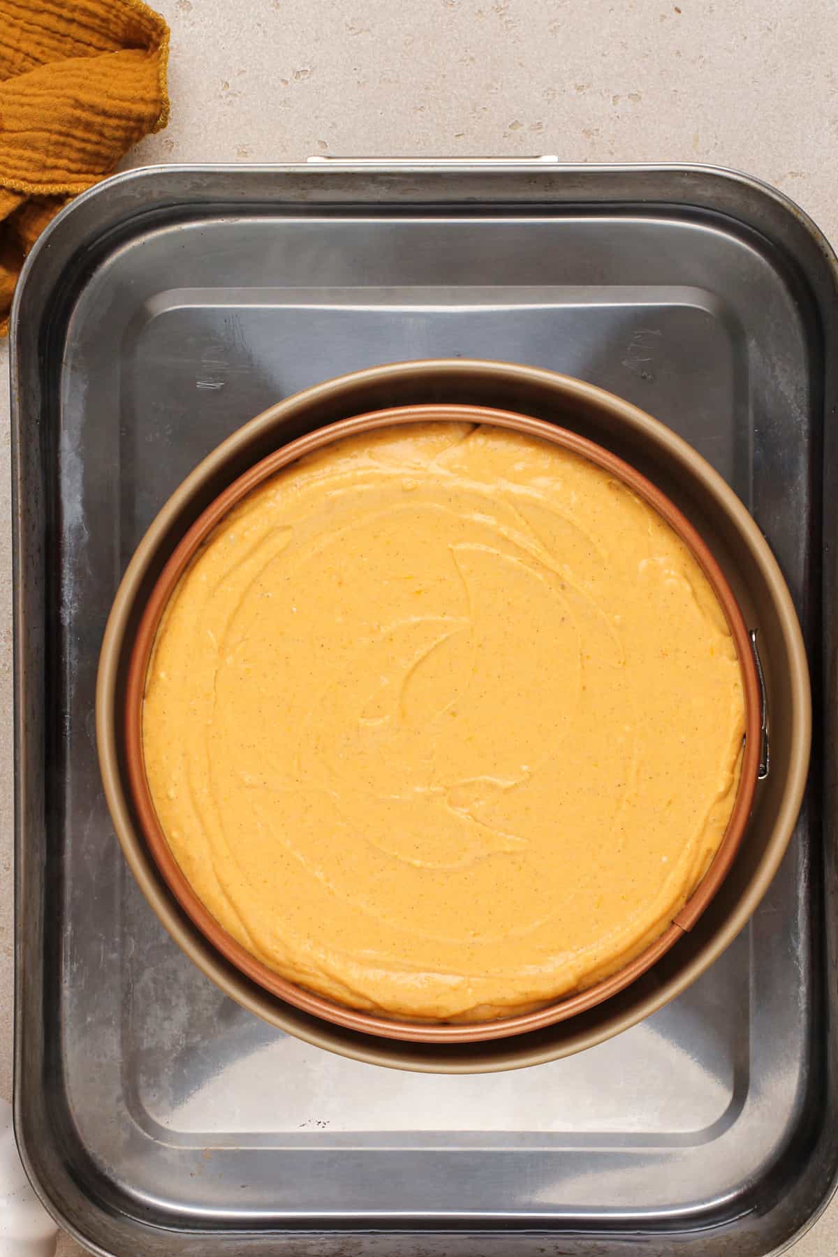 Unbaked sweet potato cheesecake in a water bath, ready to go in the oven.