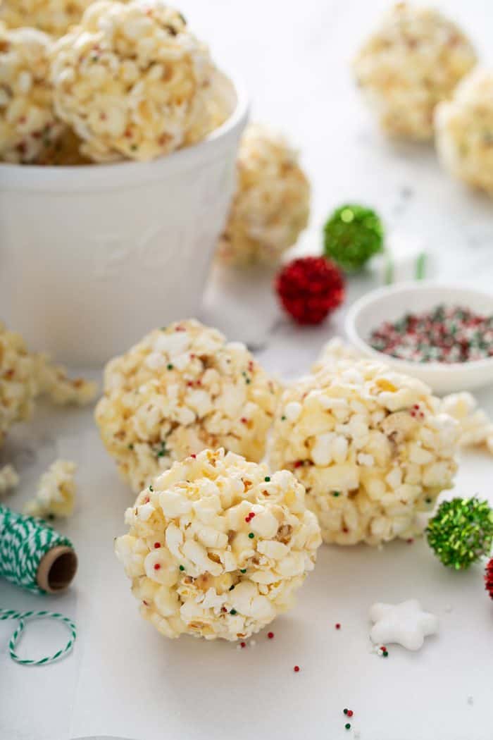 close up of popcorn balls on a counter with a white bowl in the background