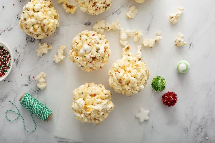 Popcorn balls on a marble countertop next to holiday baubles