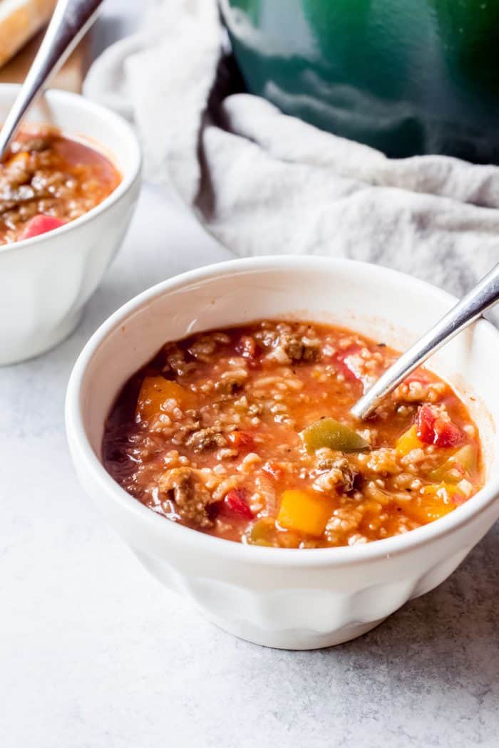 Spoon in a bowl of stuffed pepper soup with a soup pot in the background