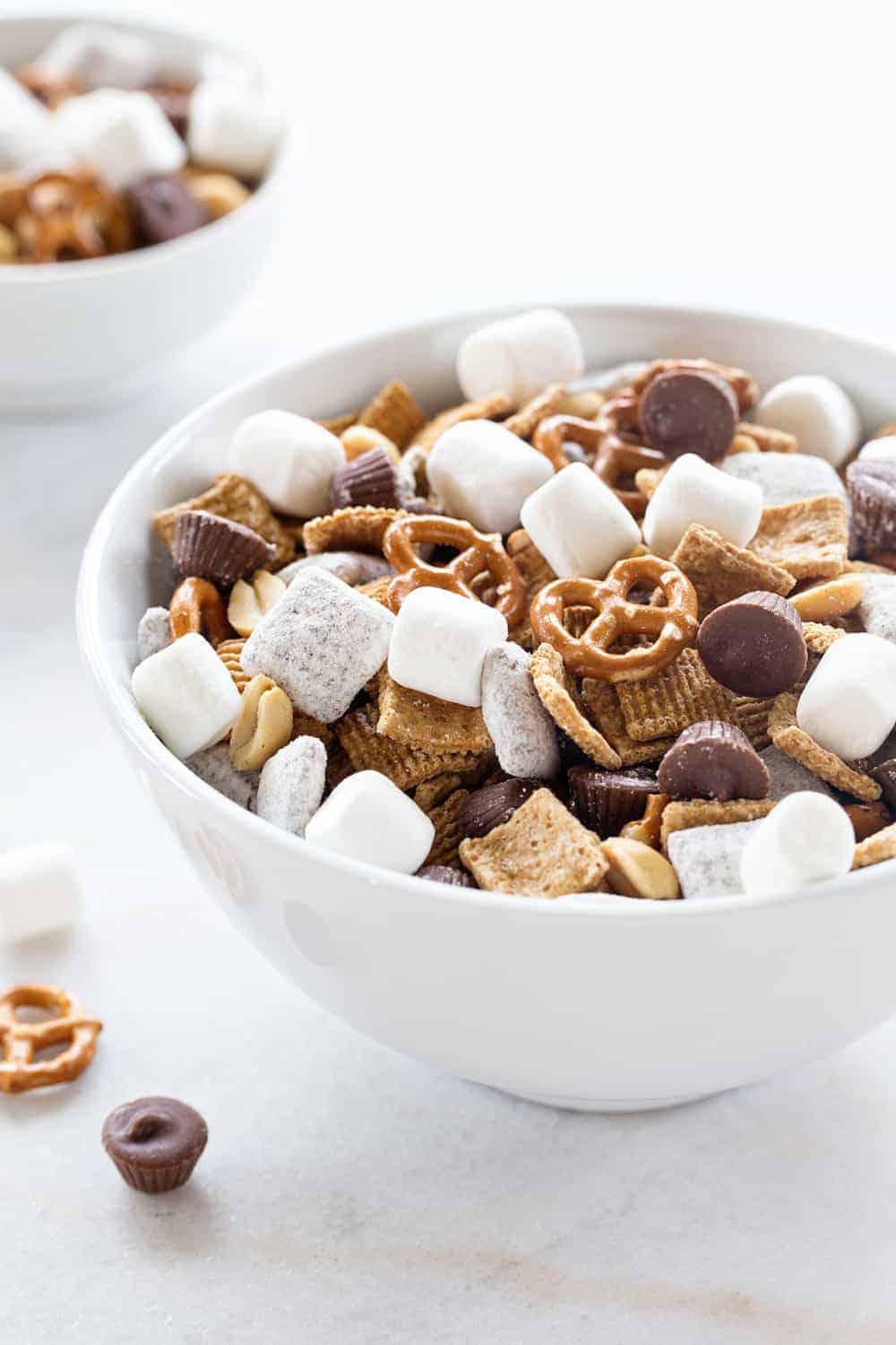 S'mores Snack Mix combines graham cereal, puppy chow, pretzels, peanuts, mini peanut butter cups and marshmallows to create the most amazing snack mix! You're going to LOVE it!