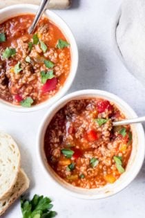 Overhead view of two bowls of stuffed pepper soup on a white counter