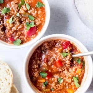 Overhead view of two bowls of stuffed pepper soup on a white counter