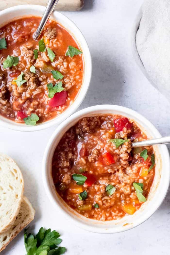 Overhead view of two bowls of stuffed pepper soup on a white counter