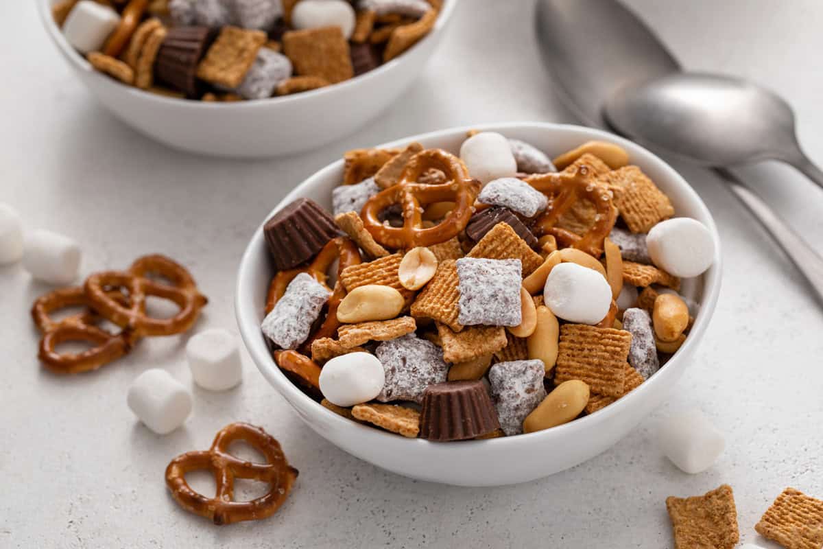 Small white bowl filled with s'mores trail mix, with a second bowl in the background.