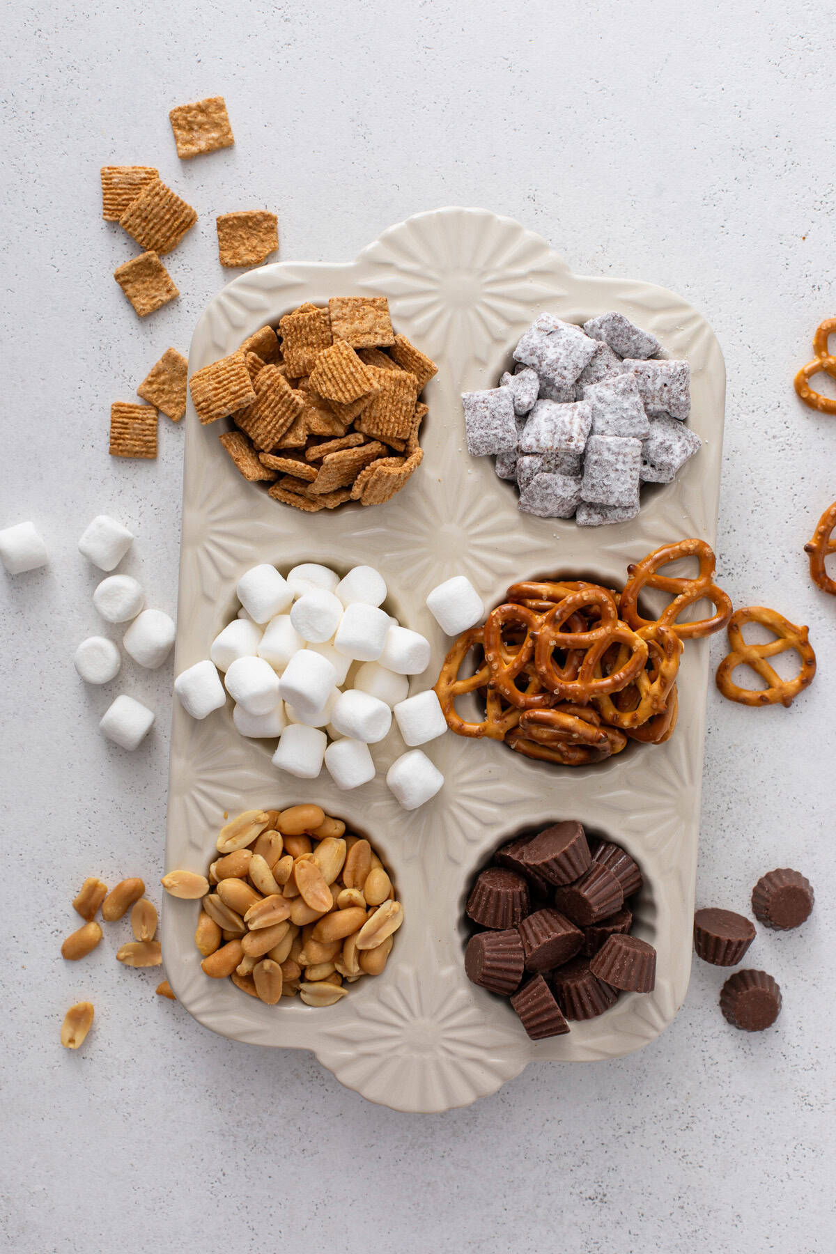 Ingredients for s'mores trail mix arranged in a 6-well muffin tin.