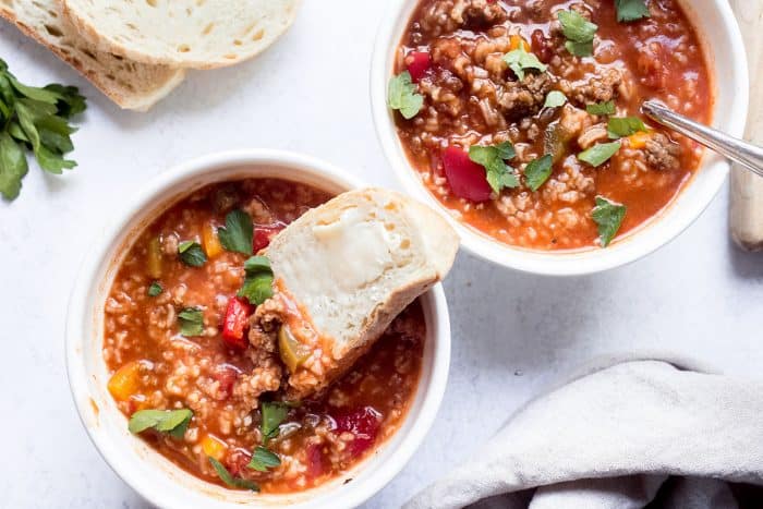 Buttered bread dipping into a bowl of stuffed pepper soup