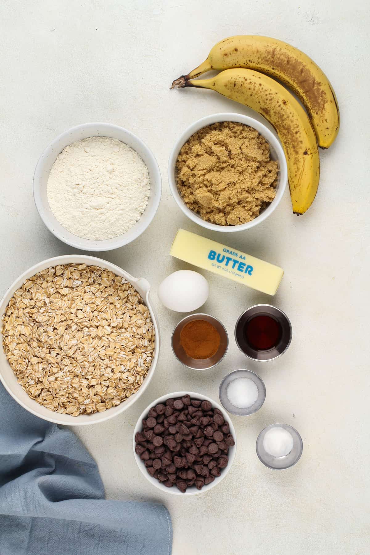 Banana oatmeal cookie ingredients arranged on a beige countertop.
