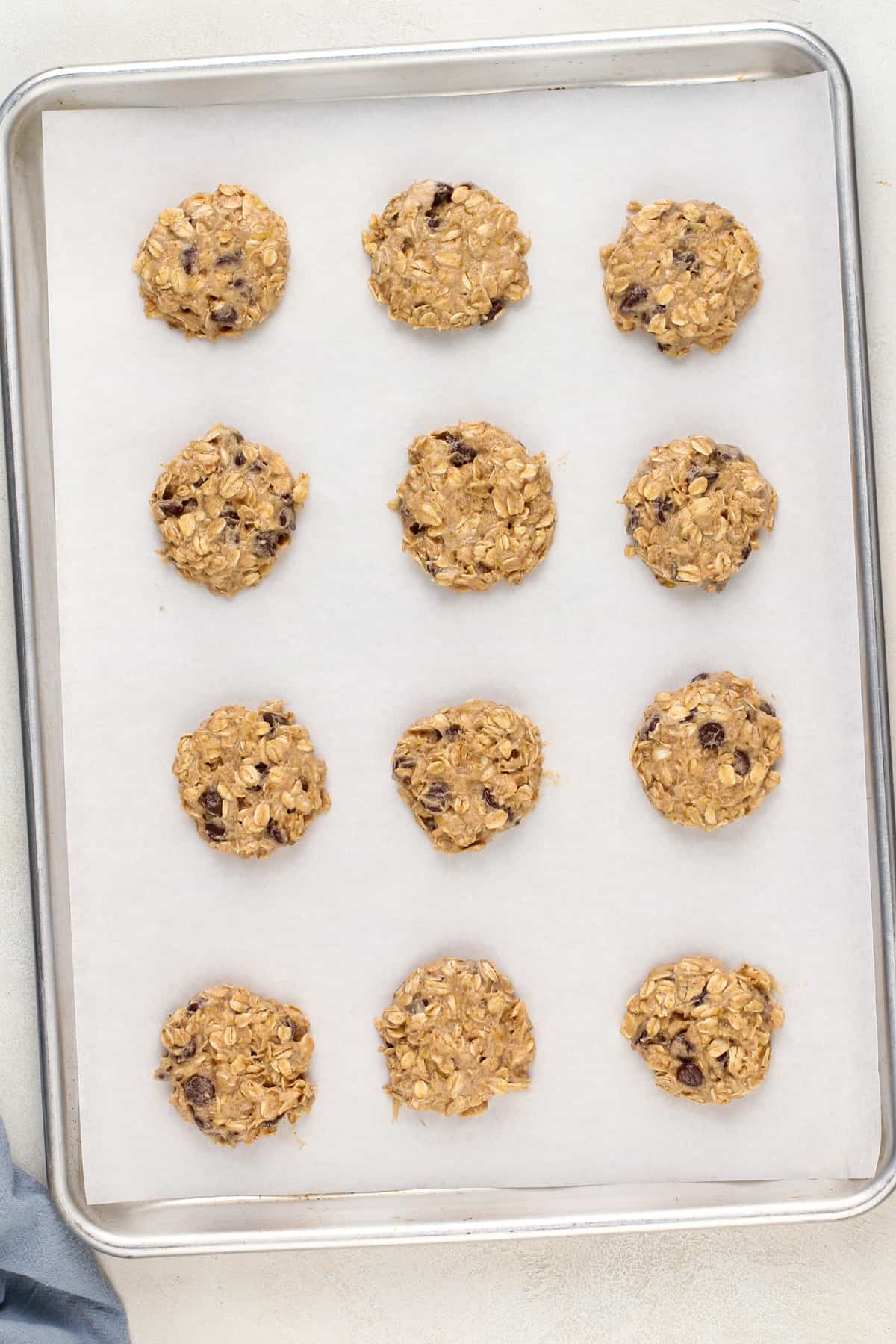 Unbaked banana oatmeal cookies on a parchment-lined baking sheet.