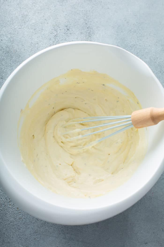Whisk combining sour cream and condensed soup in a white mixing bowl
