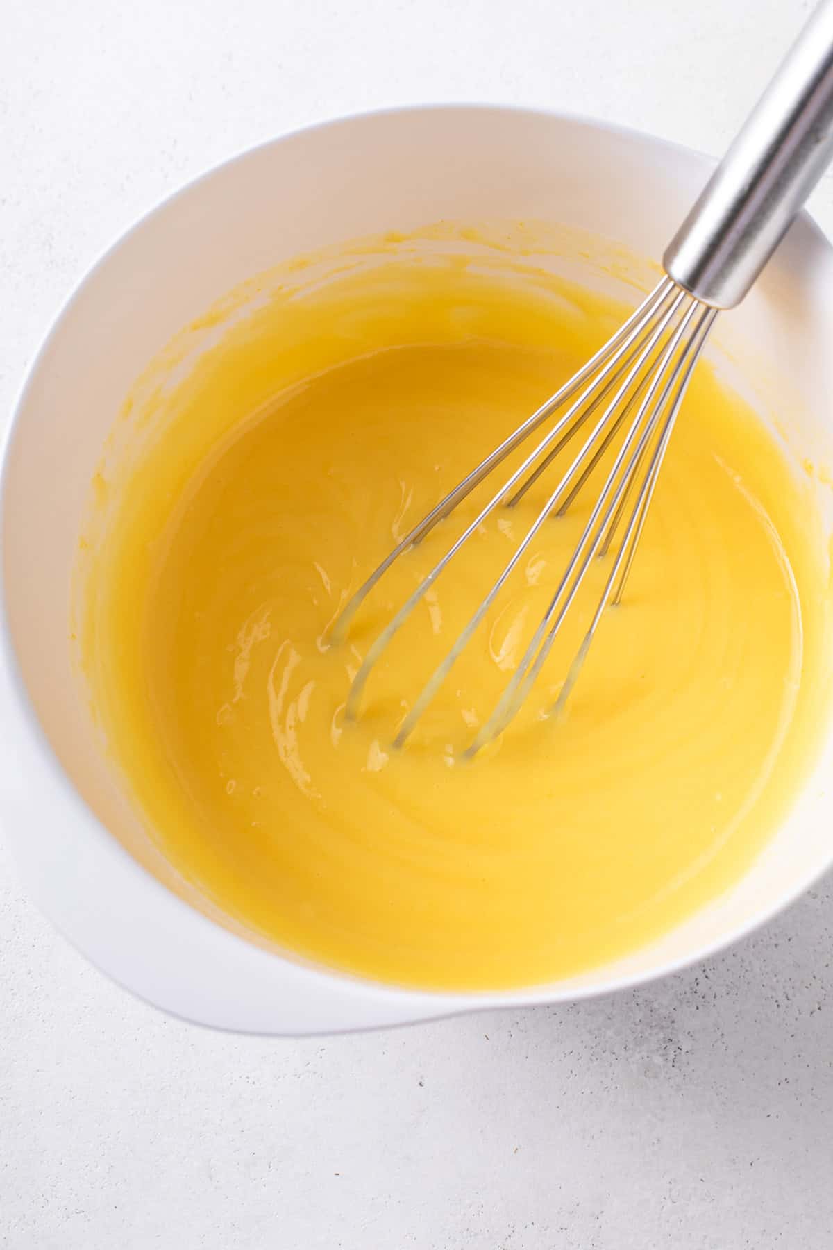 Instant pudding mix whisked with milk in a white bowl.