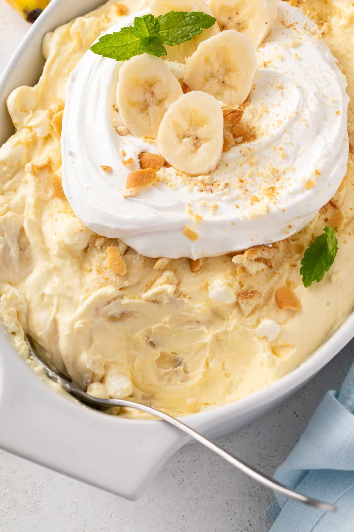 Banana pudding fluff in a white serving dish. A serving spoon is in the dish and a portion has been scooped out.