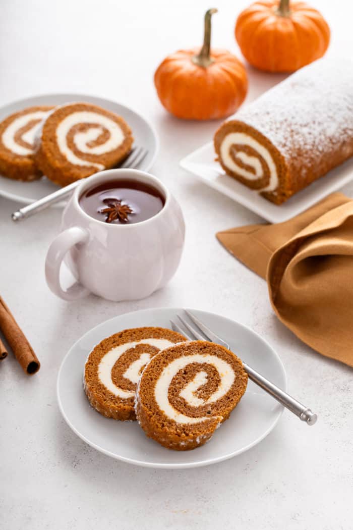 Two white plates, each holding two slices of pumpkin roll.