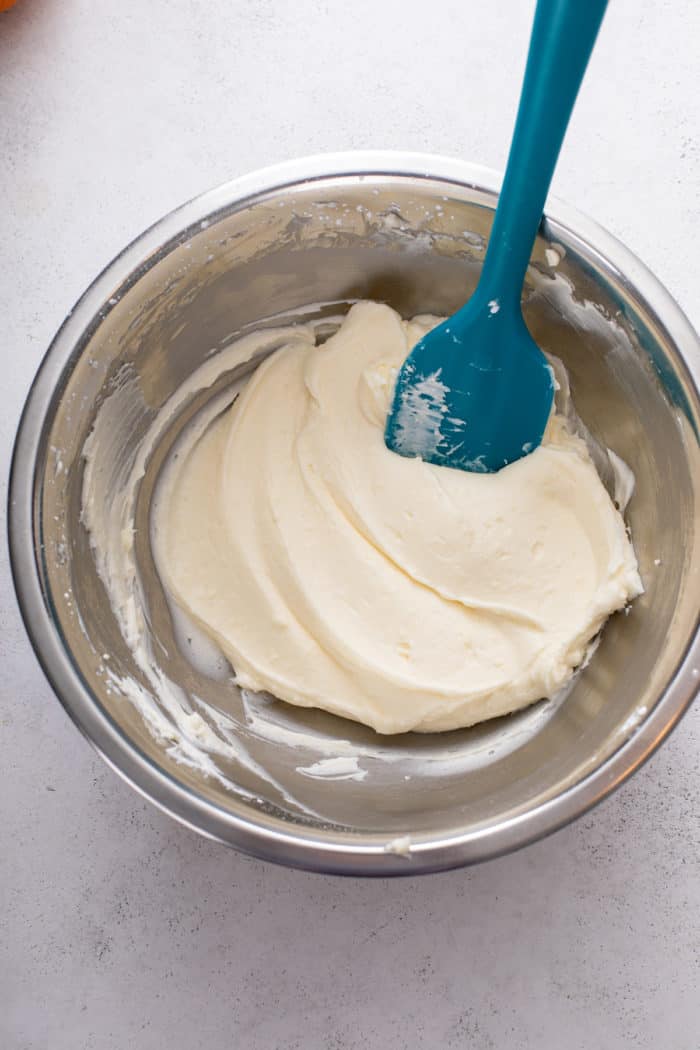 Cream cheese filling for pumpkin roll in a metal bowl.