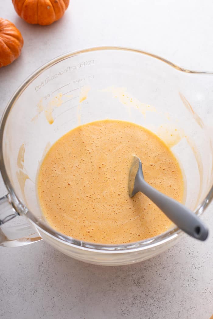 Wet ingredients for pumpkin roll in the bowl of a stand mixer.