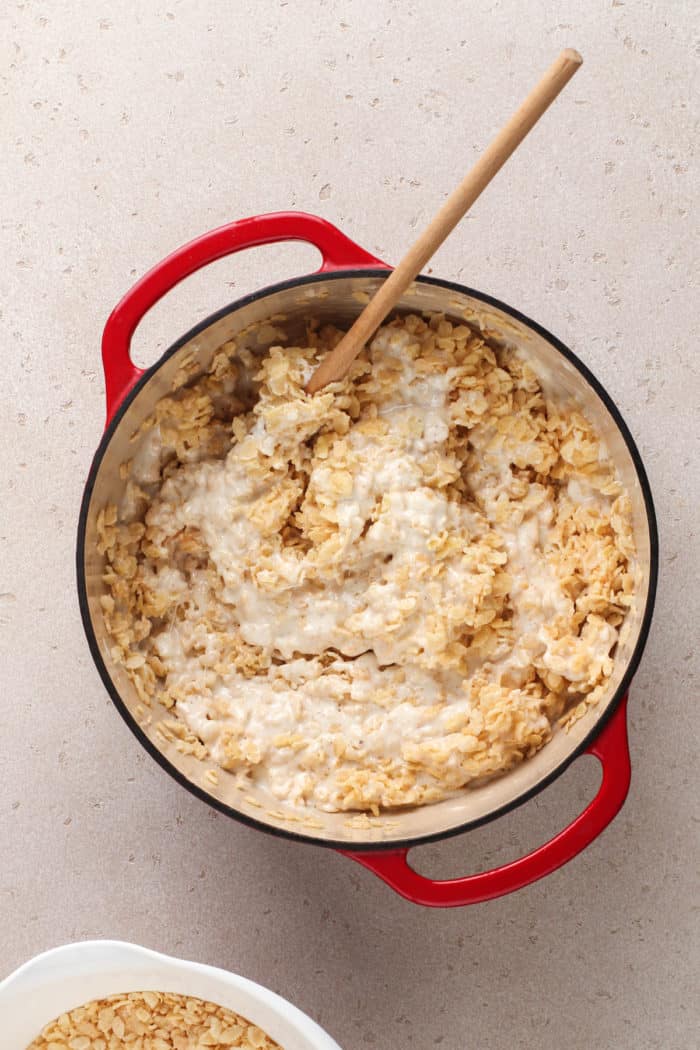 Melted marshmallows and rice krispies cereal being stirred together in a dutch oven.