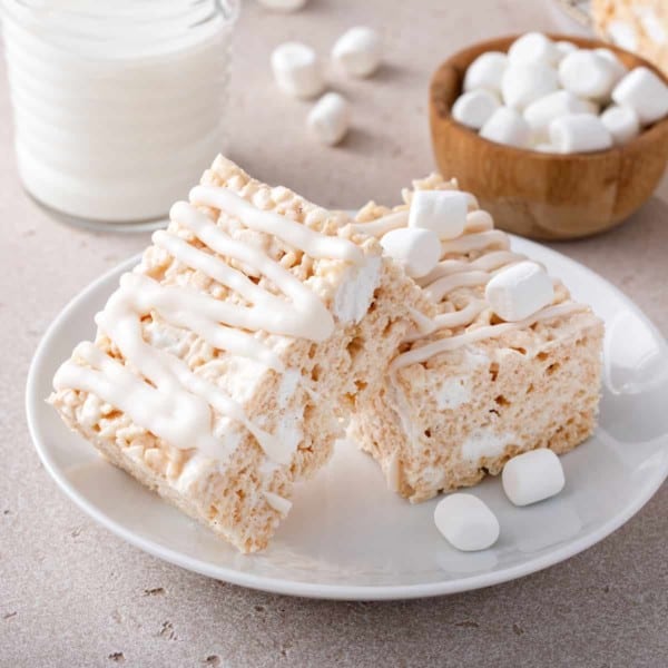 Two iced brown butter rice krispie treats on a white plate.
