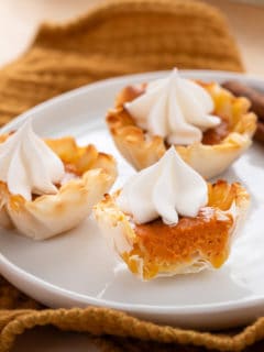 Halved mini pumpkin pie on a white plate with 2 other mini pies.