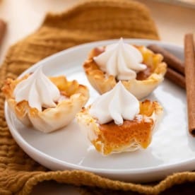 Halved mini pumpkin pie on a white plate with 2 other mini pies.