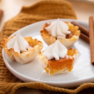 Halved mini pumpkin pie on a white plate with 2 other mini pies.