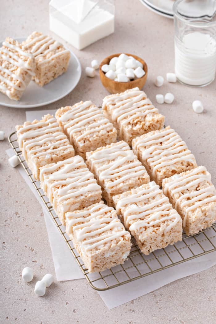 Sliced brown butter rice krispie treats, drizzled with icing, set on a wire cooling rack.