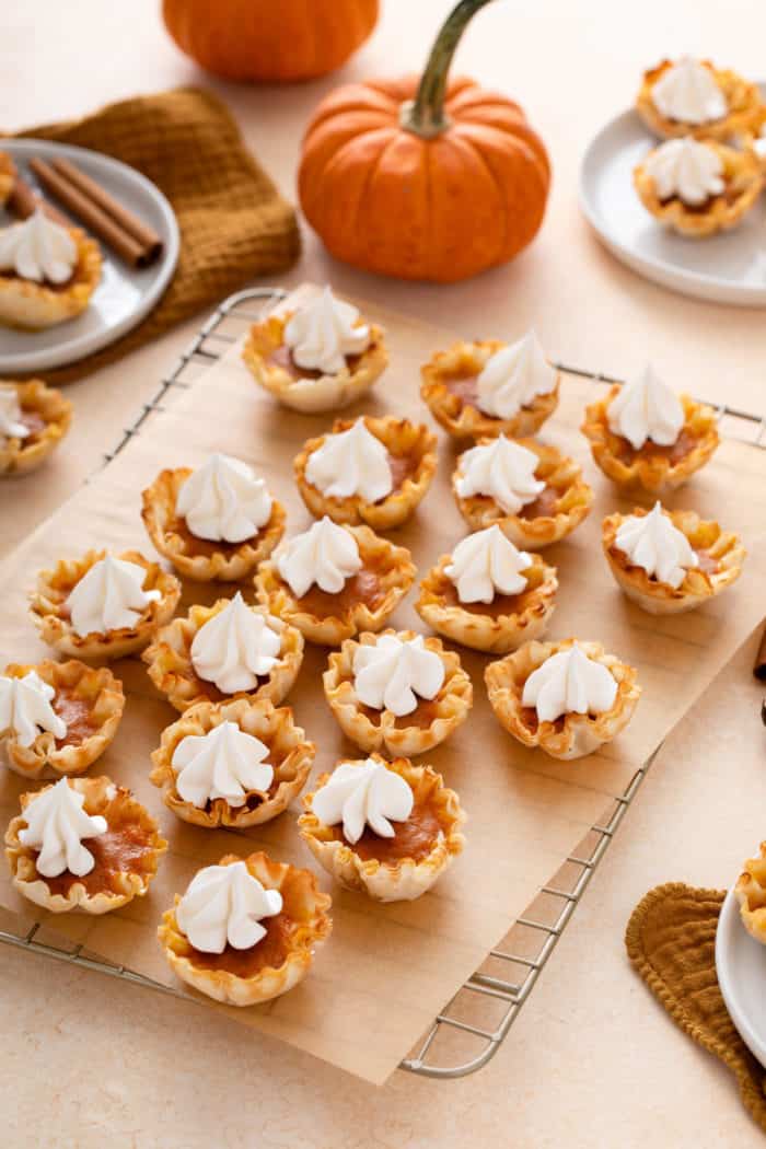 Wire rack holding mini pumpkin pies topped with whipped cream.